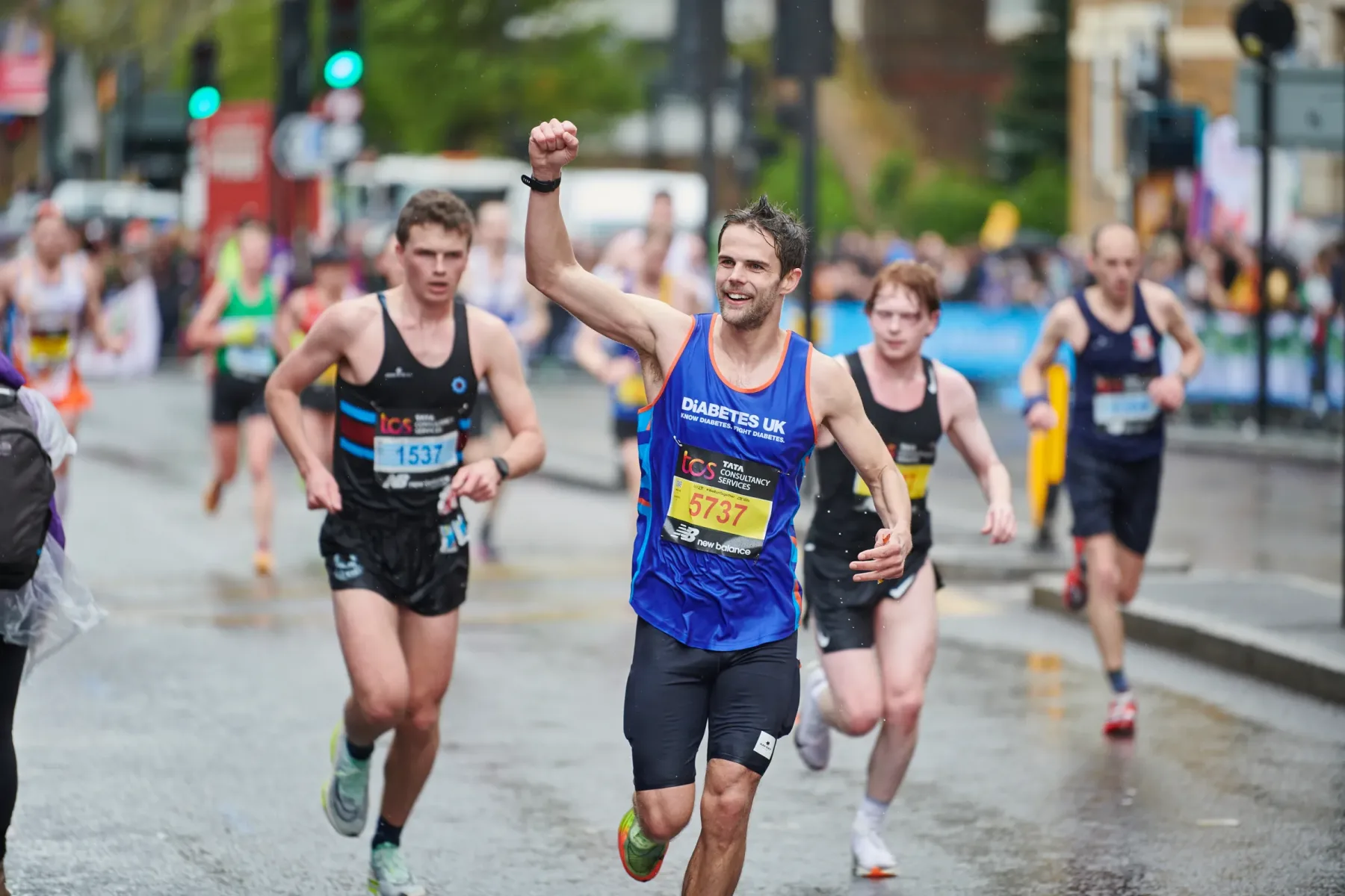 Peter mid-race, arm raised, on a wet road.